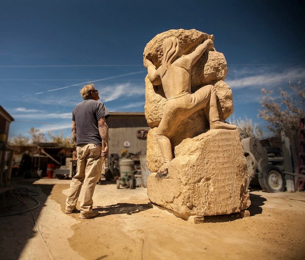 Sculptor David Falossi beside his hand-carved limestone sculpture Spirit Climb